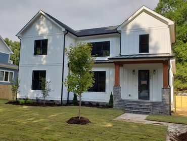 Modern two-story white house with black window frames and a landscaped lawn.