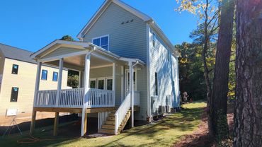 Newly built light blue house with a front porch and stairs.