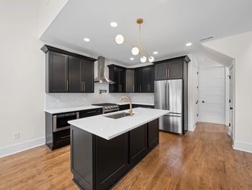 Kitchen remodel with Black Cabinets and gold Hardware with white countertops.
