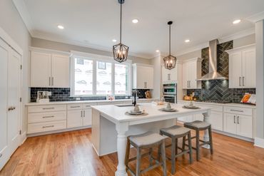 Modern white kitchen with island and pendant lighting.