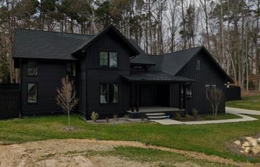 Modern black house with sleek design and surrounding trees.