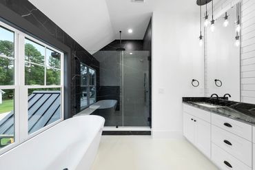 Modern bathroom with black marble shower and white freestanding tub.