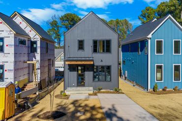 Newly constructed modern homes with different exterior colors under a clear sky.