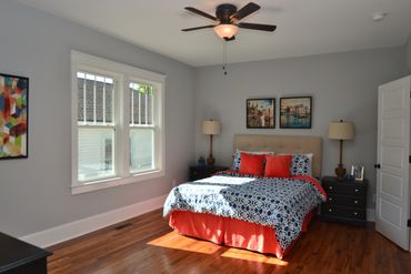 Bright bedroom with patterned bedding and hardwood floors.