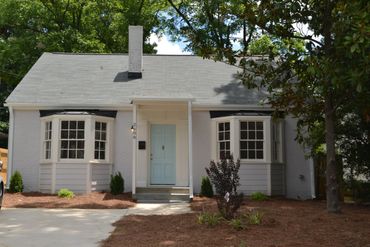 White single-story house with a light blue door and bay windows.