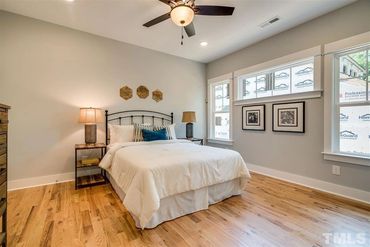 Cozy bedroom with wooden floors and natural light from large windows.