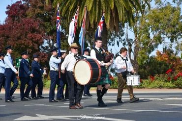 A parade with musicians and flag bearers marching outdoors.