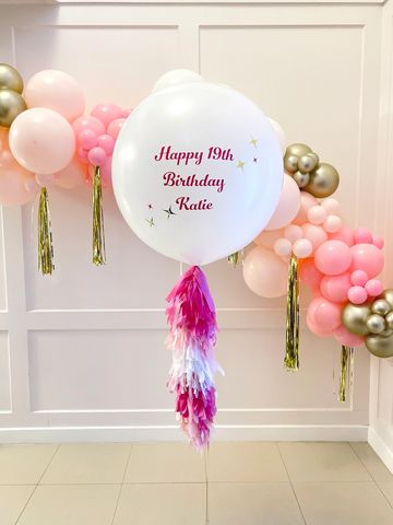 Large helium balloon with a custom inscription and custom tassels.