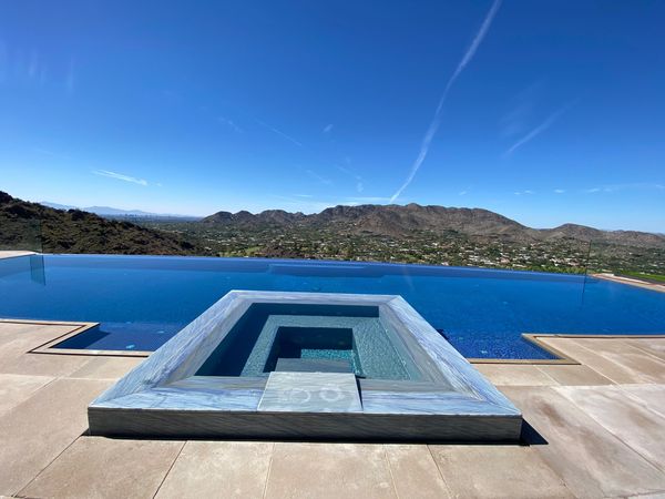 Infinity pool with a mountain view under a clear blue sky.