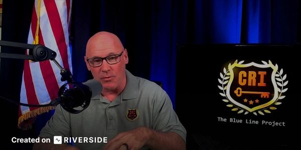Man speaking into microphone in a podcast or broadcast setting.