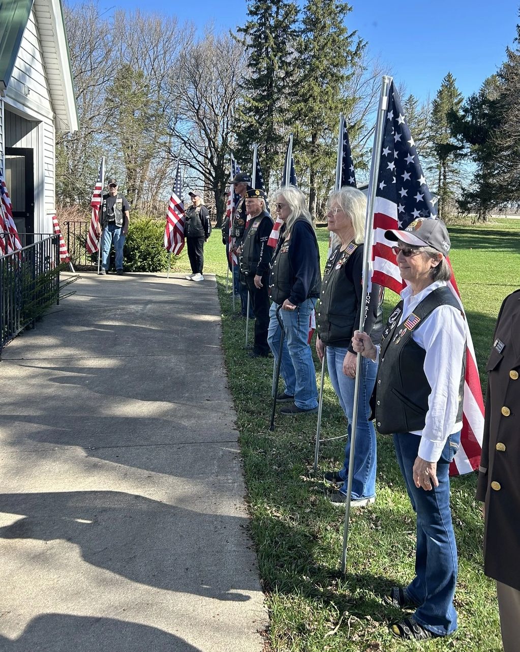 A group of veterans holding American flags outdoors near a building.