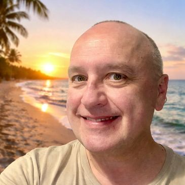 Smiling man taking a selfie on a tropical beach at sunset.