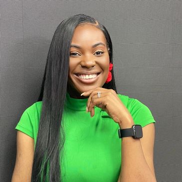 Smiling woman in a green top with long hair and a smartwatch.