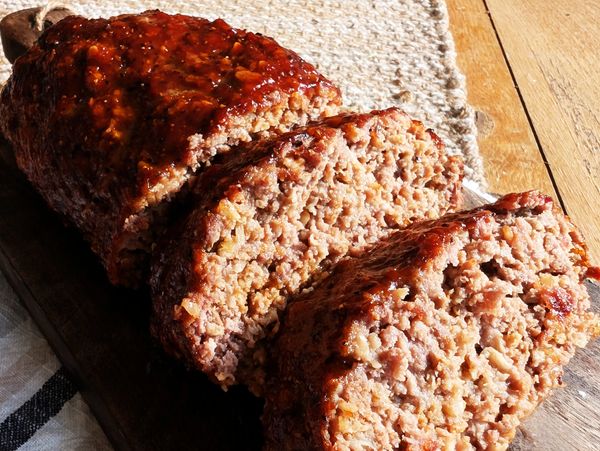 A homestyle meatloaf sliced on a wooden cutting board