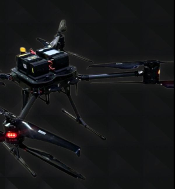 Close-up of a black drone with multiple propellers against a dark background.