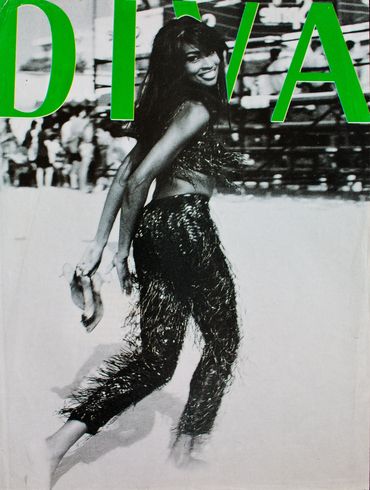 Woman dancing energetically in fringed outfit on magazine cover.