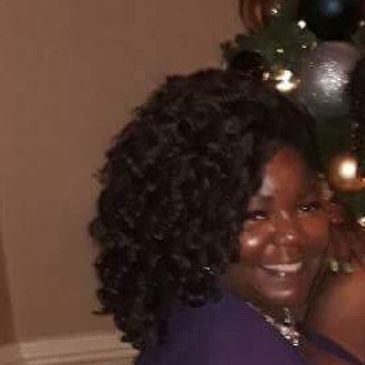 Smiling woman with curly hair in a festive setting.