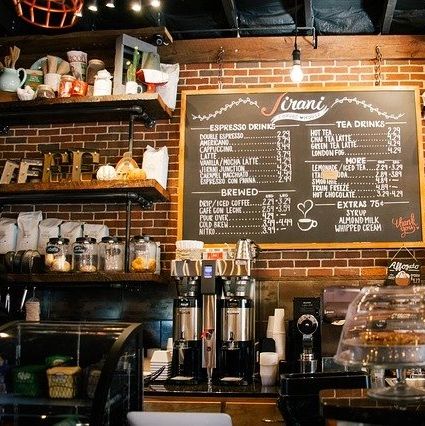 Cozy coffee shop counter with espresso machines and menu board.