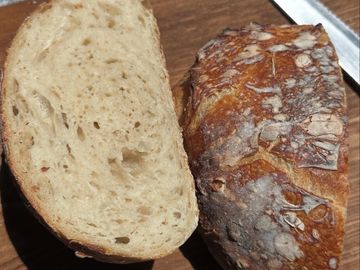 A loaf of crusty bread cut in half on a wooden surface.