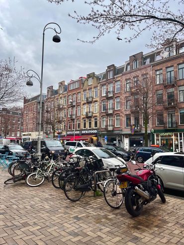 Bicycles and a motorcycle parked on a street with European-style buildings.