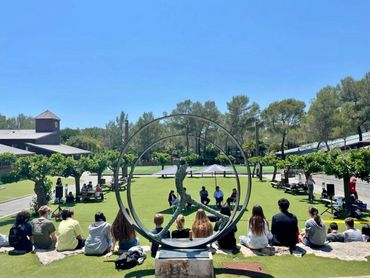 Outdoor group meeting with a sundial sculpture in the foreground.