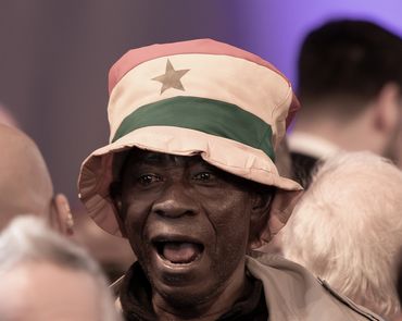 Man wearing a colorful star-patterned hat in a crowd.