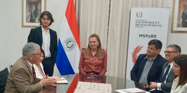 Group meeting in a formal setting with Paraguayan flag and MSPyBS banner.