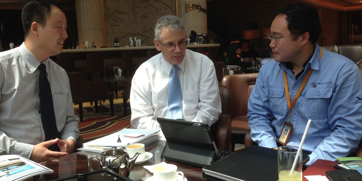 Three men having a business discussion with documents and a tablet on the table.