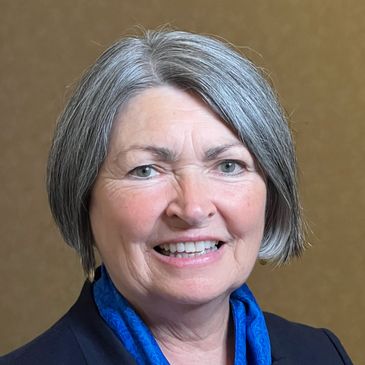 Portrait of a smiling older woman with gray hair and blue scarf.