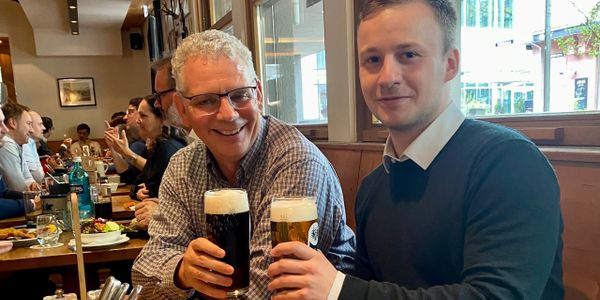 Two men enjoying beers together at a lively restaurant.