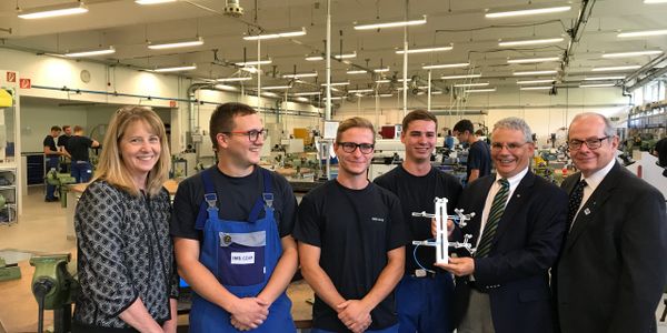 Group of people in a workshop showcasing a mechanical model.