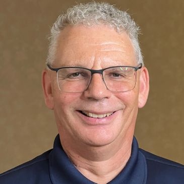 Smiling man with curly gray hair and glasses.