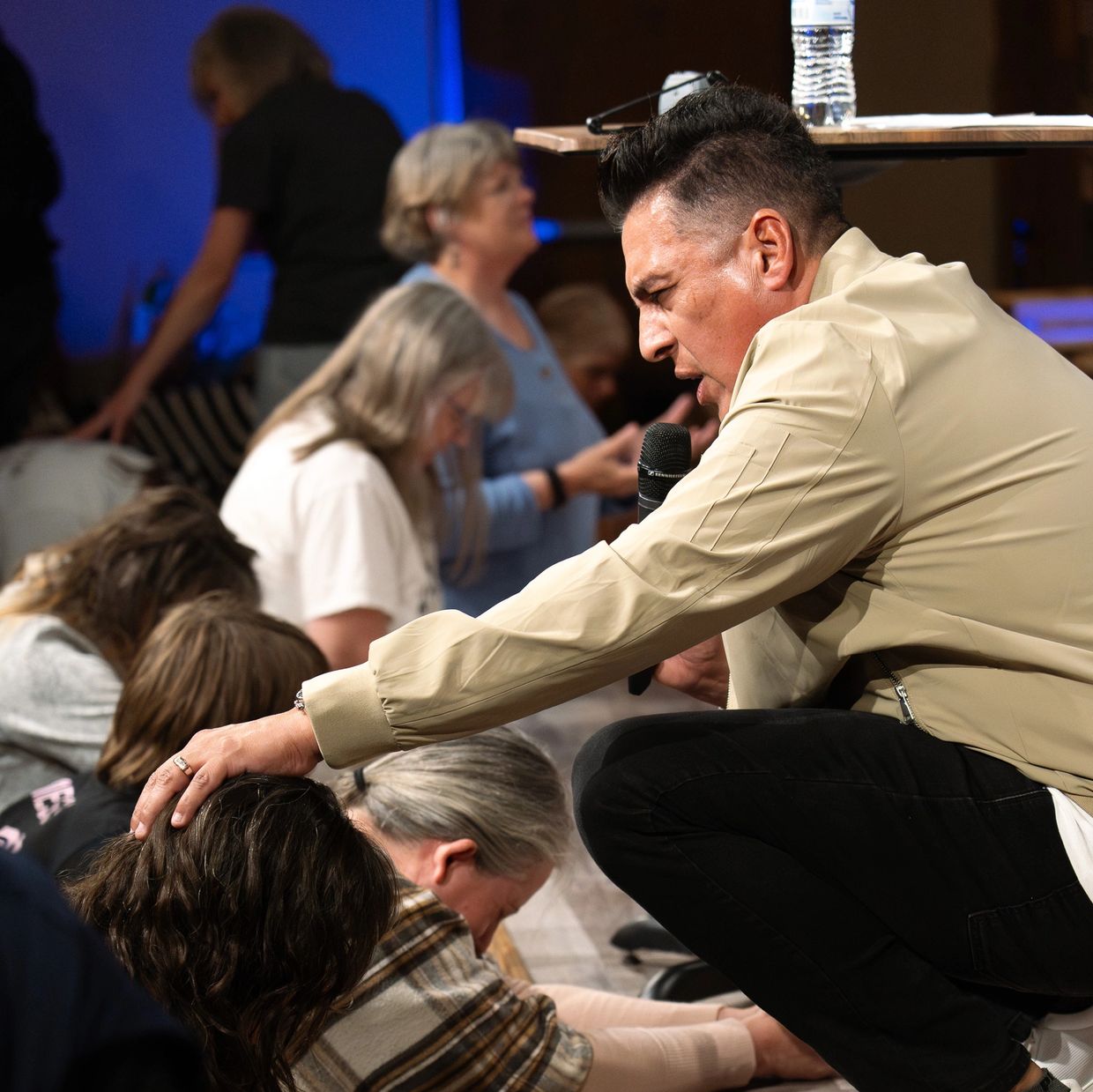 A man prays over a group of people during a spiritual gathering.