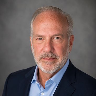 Professional headshot of a mature man with gray hair and beard.