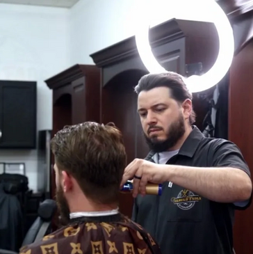 A barber cutting the hair of his client