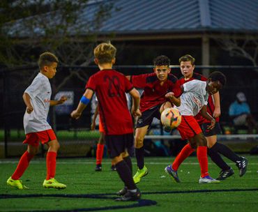 Young boys playing a competitive soccer match at night.
