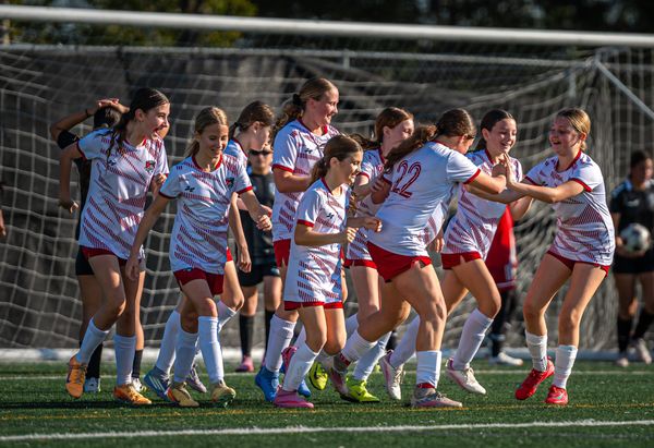 Girls soccer team celebrating joyfully on the field.