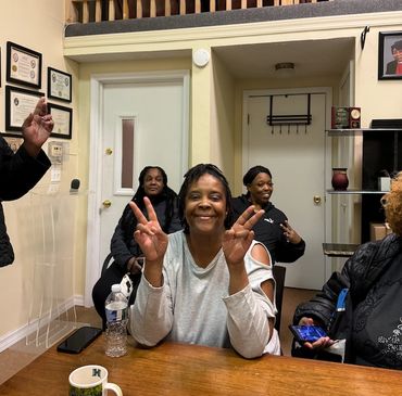 Smiling woman showing peace signs, friends in a cozy room.