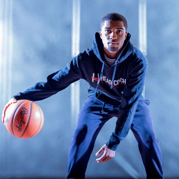 Young man in sportswear dribbling a basketball indoors.
