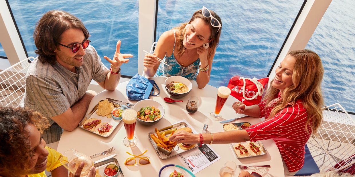 Friends enjoying a meal and drinks together by the ocean.