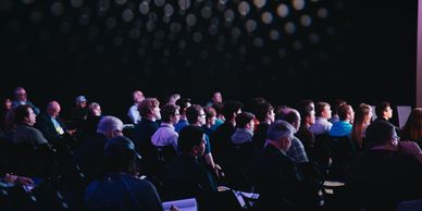 An audience of people looking in same direction towards a stage.