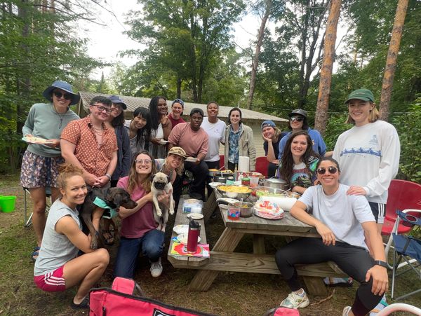 Group of friends enjoying a picnic outdoors with dogs and food.