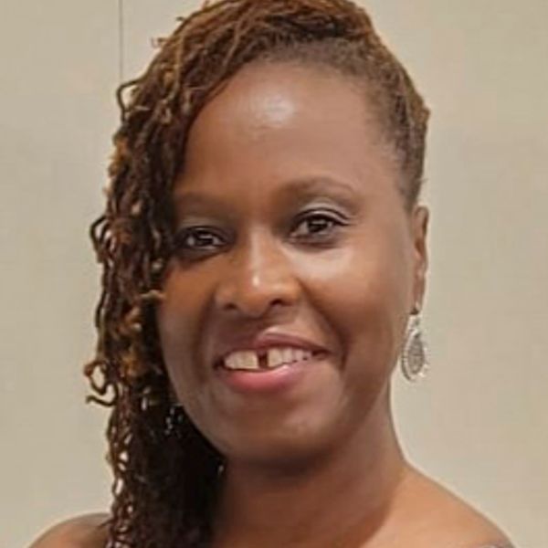 Smiling woman with braided hair and earrings.