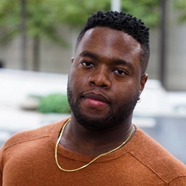 Portrait of a man wearing a brown shirt and gold chain.