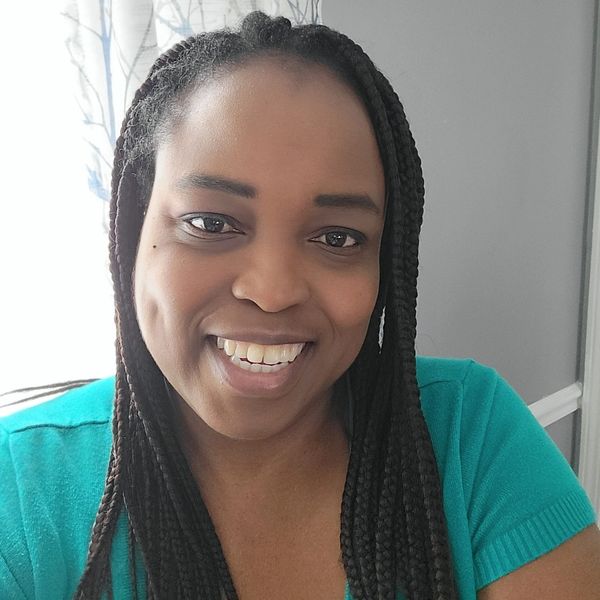 Smiling woman with braided hair in a turquoise top.