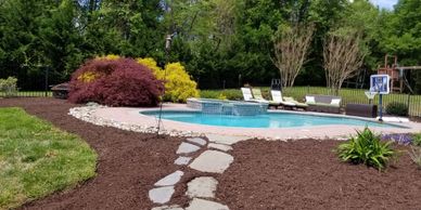 Organically dyed finely shredded hardwood mulch with landscape stones and trimmed bushes around pool