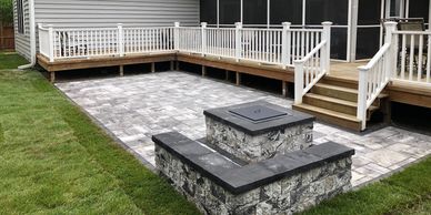 Backyard hardscape paver patio  with seating wall and fire pit leading up to back deck