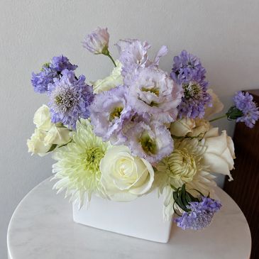 Elegant bouquet of white and purple flowers in a white vase.
