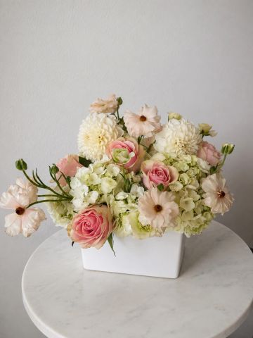 Elegant pastel flower arrangement in a white vase.