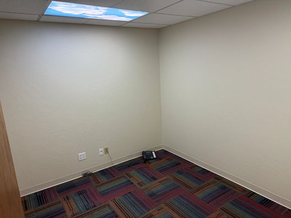 Empty office room with colorful carpet and beige walls.